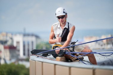 Tırmanış halatlarıyla gökdelenlerin çatısında çalışan dağcı..