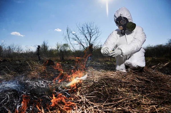 Pessoa irreconhecível queimando grama seca velha no campo — Fotografia de Stock