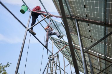 Fotovoltaik güneş paneli sistemi monte eden işçiler