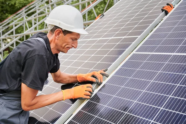 Male worker in safety helmet installing solar panel outdoors. — Stock Photo, Image