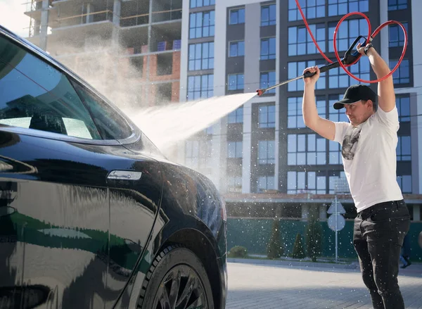 Homem lavando automóvel por pressão pistola de água. — Fotografia de Stock