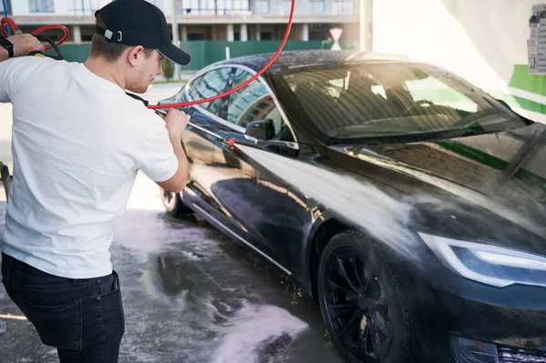 Jovem homem lavando carro com arruela de alta pressão — Fotografia de Stock