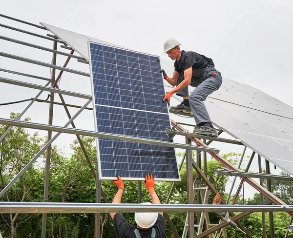 Двое мужчин устанавливают солнечную панель на открытом воздухе. — стоковое фото