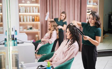 İki kuaför kuaförde kadın saçı yapıyor..