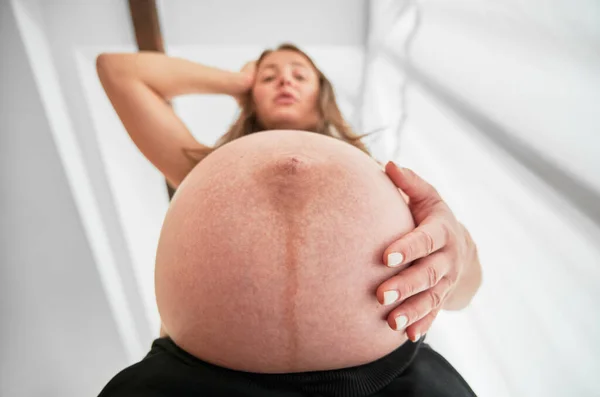 Низкий вид удивленной беременной женщины с круглым животом. — стоковое фото