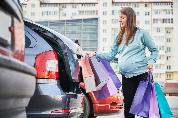 Alışveriş sonrası çanta taşıyan hamile bir kadın.