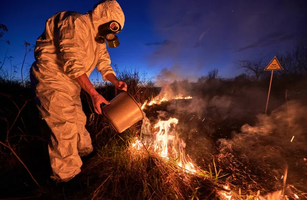 Ecologista bombeiro extinguindo incêndio no campo à noite — Fotografia de Stock