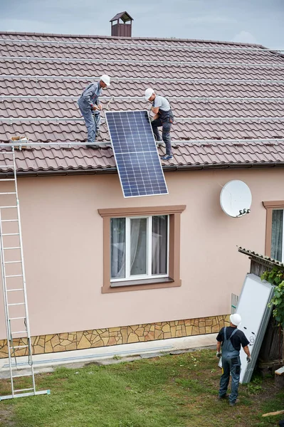 Man worker mounting solar panels on roof of house. — Stock Photo, Image