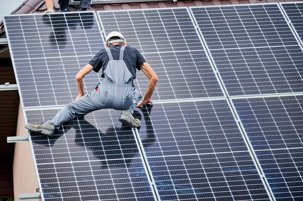 Mann montiert Solarzellen auf Hausdach. — Stockfoto