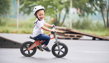 Küçük çocuk kaykay parkında bisiklet sürmeyi öğreniyor..