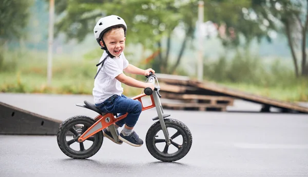 Küçük çocuk kaykay parkında bisiklet sürmeyi öğreniyor..