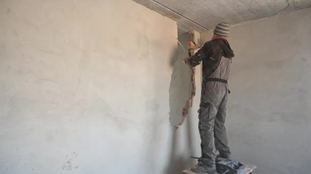 Männlicher Arbeiter durchbricht Mauer mit Vorschlaghammer in Wohnung. — Stockvideo