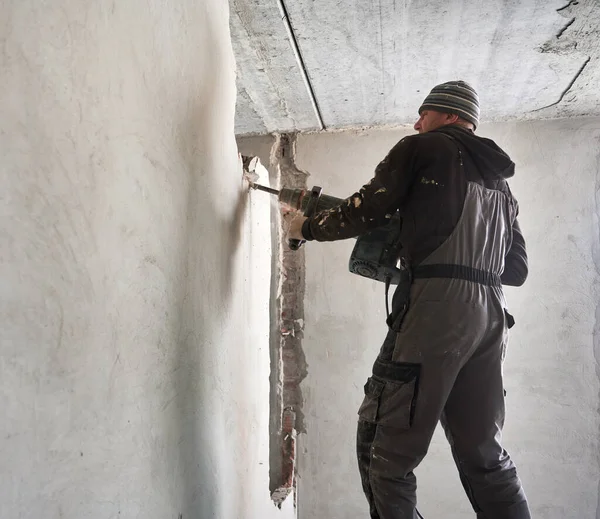 Trabajador desmontaje de la pared interior en la habitación con perforador. — Foto de Stock