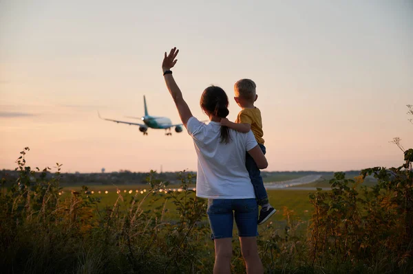 带着孩子挥手登上商业飞机的妇女 — 图库照片