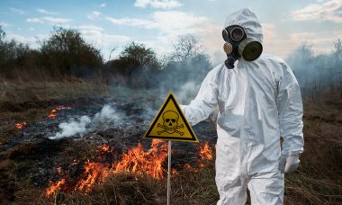 Gaz maskeli itfaiyeci ekolojist orman yangını alanında çalışıyor..