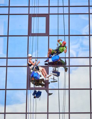 Endüstriyel dağcılık işçisi binanın penceresini temizliyor..