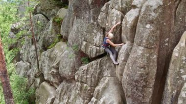 Dişi kaya tırmanışçısı dev bir kaya parçasına tırmanıyor.