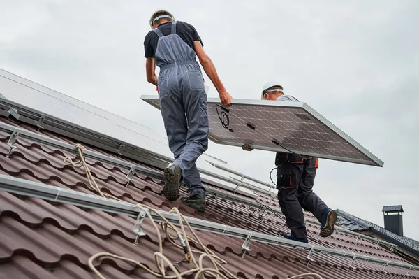 Uomo operaio montaggio pannelli solari sul tetto della casa. — Foto Stock