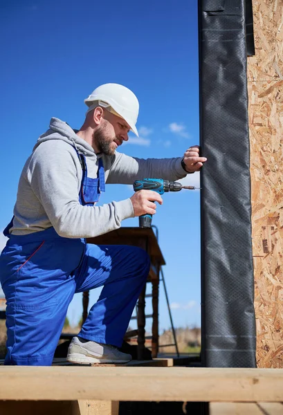 Constructor que instala la hoja de hierro corrugado utilizada como fachada de la futura casa de marco de madera. — Foto de Stock