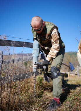 Erkek işçi ahşap çerçeve için temel kazıyor..