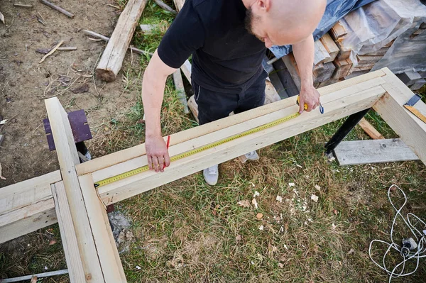 Man worker building wooden frame house on pile foundation. — Stockfoto
