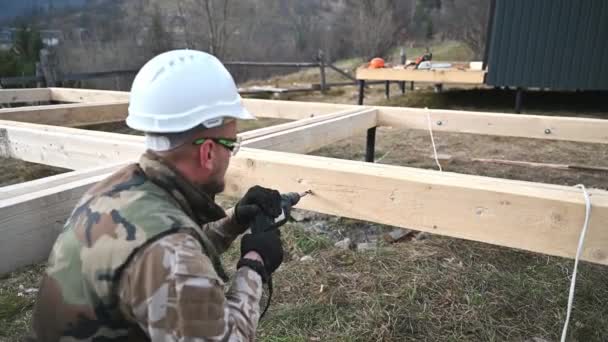 Homem trabalhador construção de madeira quadro casa na fundação pilha. — Vídeo de Stock