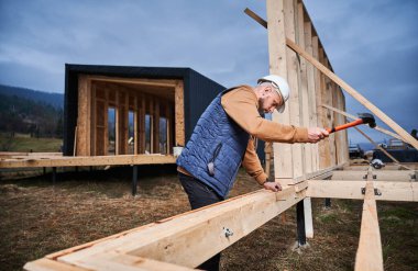 Ahşap çerçeve inşa ederken çekiç kullanan bir adam..