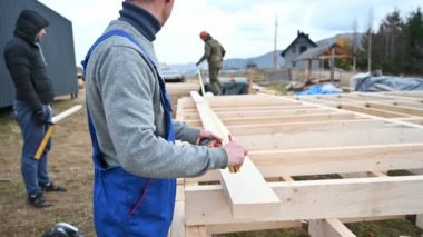 Man worker building wooden frame house on pile foundation.