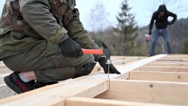 Muž pracovník bušení při stavbě dřevěný rám domu. — Stock video