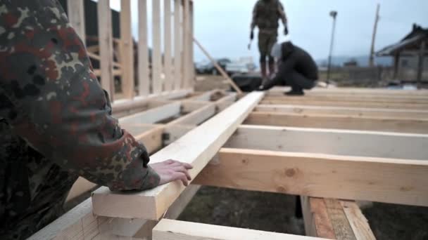 Człowiek pracownik budowy drewnianej ramy domu na fundamencie stosu. — Wideo stockowe