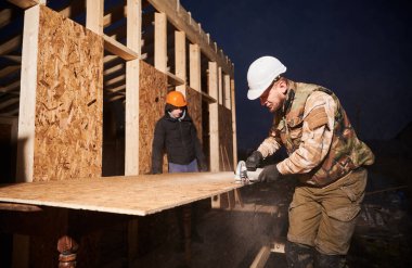 Marangoz, ahşap çerçeve yapmak için OSB tahtasını kesmek için dairesel testere kullanıyor..