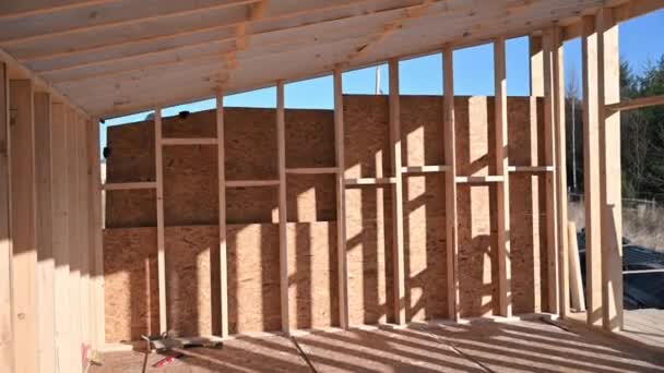 Man worker building wooden frame house, mounting wooden OSB board. — Stok video