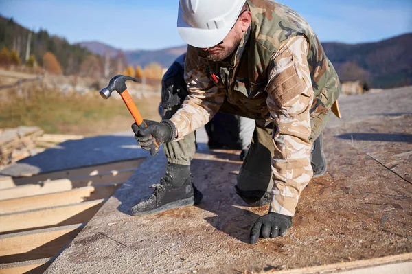 Marangoz, tahta çerçeve inşa ederken OSB paneline çivi çakıyor..