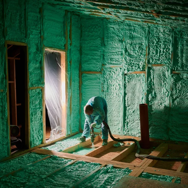 Worker spraying polyurethane foam for insulating wooden frame house. — Foto de Stock