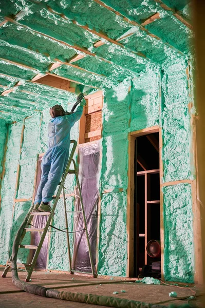 Schiuma di poliuretano spruzzante del lavoratore per la casa di legno isolante della struttura. — Foto Stock