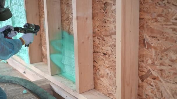 Worker spraying polyurethane foam for insulating wooden frame house. — Stock videók