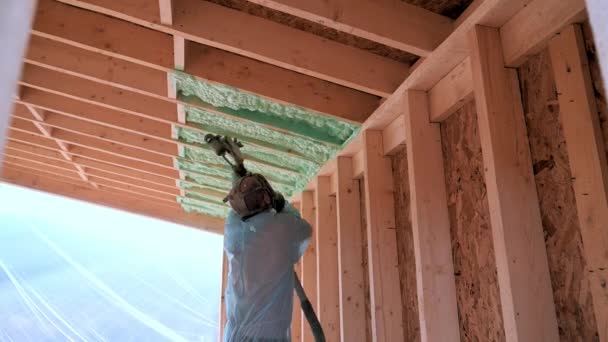 Worker spraying polyurethane foam for insulating wooden frame house. — Wideo stockowe