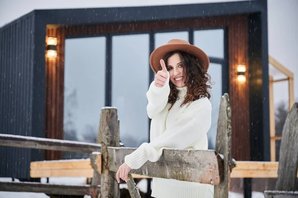Woman enjoying winter holidays on terrace of contemporary barn house in the mountains. — Stockfoto