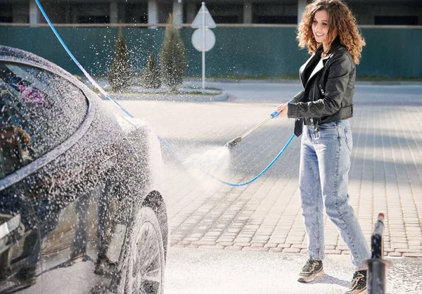 Menina espumante auto em lavagem de carro por pistola de pressão. — Fotografia de Stock