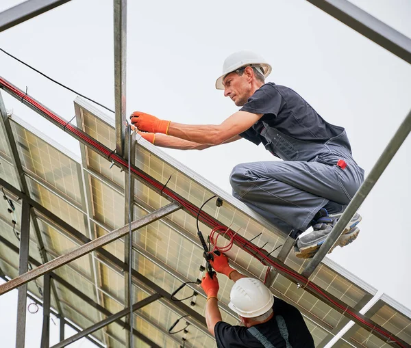 Travailleurs masculins montage système de panneaux solaires à l'extérieur. — Photo