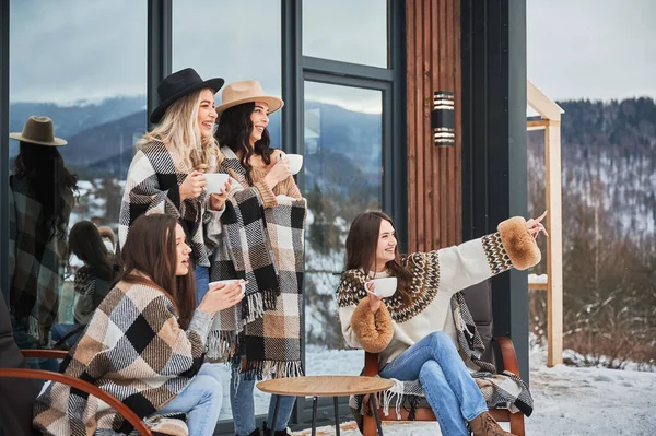 Young women enjoying winter weekends on terrace of contemporary barn house.