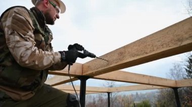 Ahşap çerçeve inşa eden adam. Gelecekteki kulübelerin ahşap çerçevesinde elektrikli matkapla delik açan işçiler. Marangozluk kavramı.