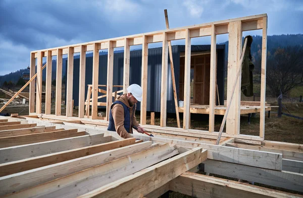Yığınla temele ahşap çerçeve inşa eden bir işçi. Marangoz çekiçle tahta çivi çakıyor. Marangozluk kavramı.