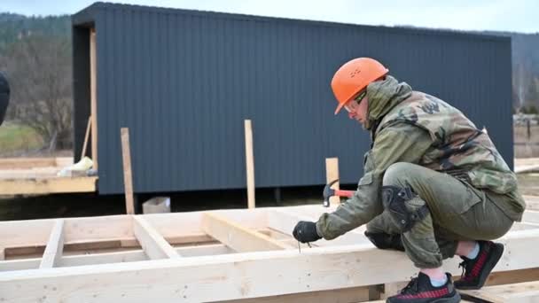 工人在桩基础上建造木制框架房屋 木匠用铁锤把钉子锤入木板 木匠概念 — 图库视频影像