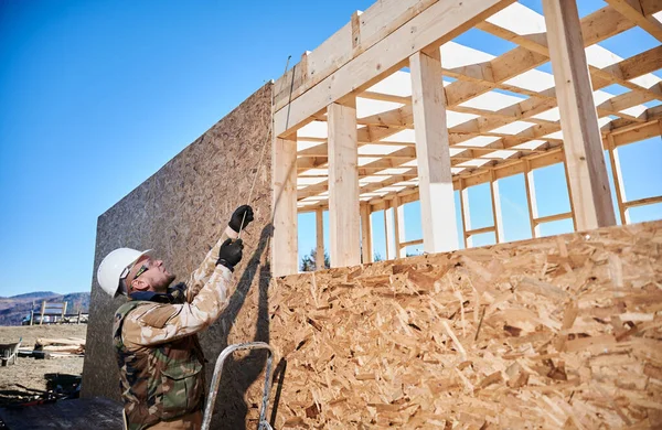 Ahşap çerçeve inşa eden bir işçi. Marangoz tahta ölçmek için mezura kullanıyor. Marangozluk kavramı.