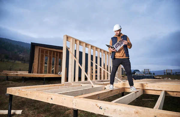 Männlicher Tischler Baut Holzrahmenhaus Auf Pfahlfundament Bauarbeiter Steht Mit Schutzhelm — Stockfoto