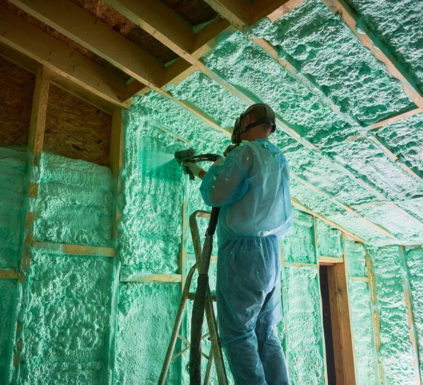 Male Builder Insulating Wooden Frame House Man Worker Spraying Polyurethane — стоковое фото