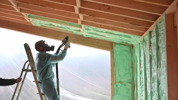 Άντρας Οικοδόμος Μόνωση Ξύλινο Σπίτι Πλαίσιο Εργάτης Ψεκάζει Αφρό Πολυουρεθάνης — Αρχείο Βίντεο