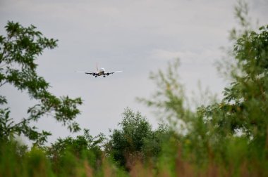 Gökyüzünde uçan ticari uçak. Bulutlu bir havada uçağın inişi ön planda. Seyahat kavramı.