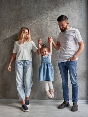 Yeni inşa edilmiş bir apartmanın duvarına dayanmış çocuklu mutlu bir aile. Sevimli kızın elini tutan kadın ve erkek ve çocuk yeni evinde havaya kaldırılıyor..